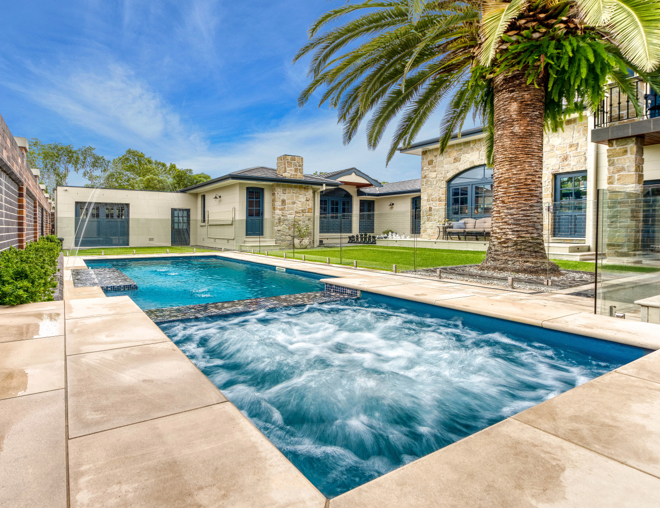 Luxury pool and spa installation by Integrity Pools featuring stone work and tropical landscaping